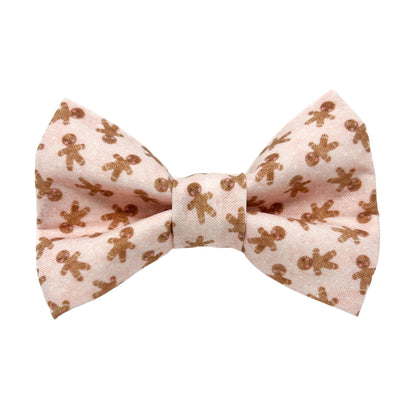 A pink dog bow tie with a gingerbread men cookie design.