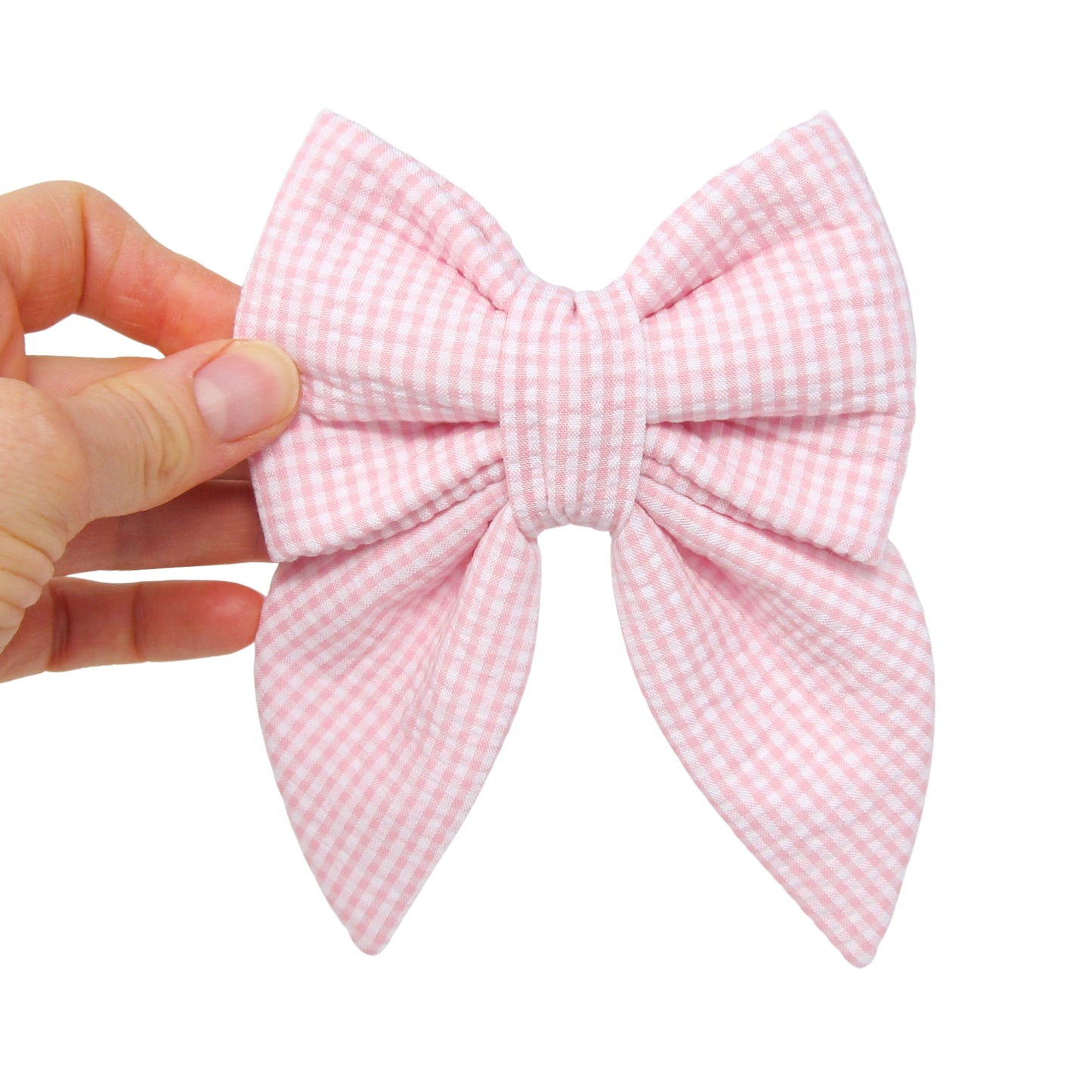 Pink gingham bow held by a hand on a white background